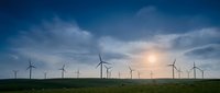 Wind turbines dotting a green landscape at sunset, symbolizing renewable energy and sustainable power generation for environmental and industrial projects.