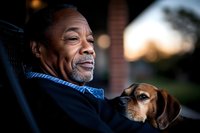 Senior African American man relaxing outdoors with his beloved beagle dog companion during golden hour sunset creating warm intimate moment.