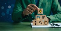 Business professional in green shirt stacking wooden blocks with innovation symbols including lightbulb, AI, gears and question mark for creative problem solving.