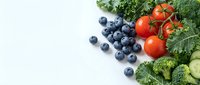 Fresh organic vegetables and blueberries arranged on white background with copy space for healthy eating and nutrition concepts.