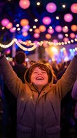 Happy young boy celebrating with raised arms at festive evening event with colorful bokeh lights and decorations creating magical atmosphere.