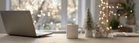 Cozy Christmas workspace with laptop, coffee mug and decorative trees on wooden desk with warm bokeh lights creating festive holiday atmosphere for remote work.