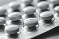 Close-up macro shot of white round pills in blister pack with selective focus and shallow depth of field in black and white monochrome style.
