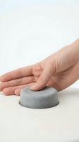 Hand touching soft gray foam dome on white surface, demonstrating product texture and comfort for skincare, wellness, and tactile design applications.