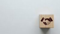 Wooden cube with handshake symbol on neutral background representing business partnership, teamwork and professional collaboration concepts.