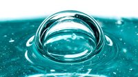 Water droplet creating ripples and waves on turquoise surface, abstract liquid motion for backgrounds and design projects.