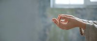 Woman's hand in meditation mudra gesture with soft natural lighting creating peaceful mindful moment for wellness and spiritual practice.
