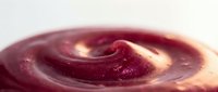 Creamy swirl of rich dark berry puree with smooth texture and glossy finish, captured in close-up macro detail on a light background.