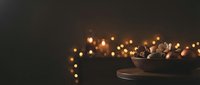 Wooden bowl filled with dried flowers and foliage arranged with warm golden string lights creating cozy autumn or holiday home decor ambiance.