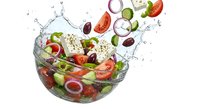 Fresh vegetables splashing into glass bowl with water droplets creating dynamic salad preparation scene for healthy cooking and nutrition concepts.