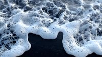 Dramatic aerial view of ocean waves creating white foam patterns against dark water, abstract natural texture showing turbulent sea movement and dynamics.