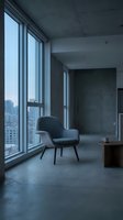 Modern minimalist loft interior with floor-to-ceiling windows overlooking city skyline, featuring contemporary black lounge chair and concrete finishes for urban living spaces.