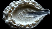Creamy white meringue dessert with decorative piped edges and smooth center, isolated on black background for culinary presentations.