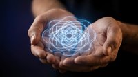 Hands of adult male with medium skin tone holding glowing atomic nucleus model, symbolizing science, energy, and innovation for educational and technology concepts.