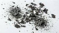 Crushed charcoal and ash particles scattered on white surface, suitable for art, design, texture backgrounds, and creative projects.