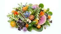 Fresh microgreens salad with colorful radish slices, cherry tomatoes and edible flowers on white background. Healthy organic superfood mix for restaurants.