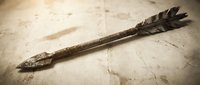 Rustic wooden arrow with feathers lying on weathered stone surface, primitive hunting tool with natural textures and earthy tones for outdoor adventure themes.