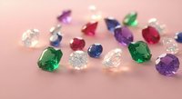 Colorful precious gemstones collection with emeralds, sapphires, rubies and diamonds scattered on pink background for jewelry design and luxury concepts.