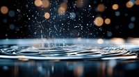 Water drop splash creating concentric ripples on dark surface with golden and blue bokeh lights, macro photography capturing liquid motion and reflection.