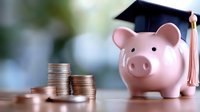 Pink ceramic piggy bank wearing graduation cap with tassel next to stacked coins on reflective surface against soft blurred background, representing education savings and financial planning.