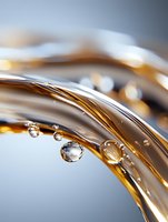 Macro shot of golden liquid waves with transparent water droplets creating abstract curves and reflections on soft blue background.