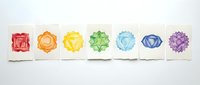 Chakra symbols in rainbow colors arranged in sequence on white cards, representing energy centers for wellness, meditation, yoga practice, and spiritual healing applications.
