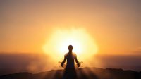 Person meditating in lotus position silhouetted against bright sunrise or sunset sky, peaceful mindfulness practice on mountain peak for wellness and spirituality.
