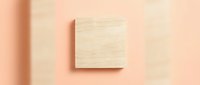 Wooden square block on a soft peach background with subtle shadows, minimal flat lay composition for product mockup or branding design.