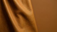 Close-up of cognac leather fabric with natural texture and folds, suitable for fashion, upholstery, and design projects.