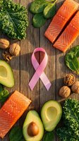 Pink awareness ribbon surrounded by healthy foods including salmon fillets, avocado halves, leafy greens, walnuts, and ginger on wooden surface for nutrition and wellness campaigns.