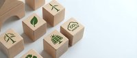 Wooden blocks with green eco icons including wind turbine, leaf, solar panel, and CO2 neutral cloud arranged on white surface for sustainability concept.