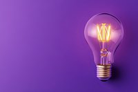 Glowing vintage filament light bulb with warm orange illumination on vibrant purple background, minimal composition with copy space for creative concepts.