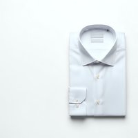 White dress shirt with collar and long sleeves folded neatly on light background for business wardrobe and professional attire concepts.