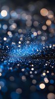 Magical blue glitter sparkles with blurred bokeh lights creating dreamy atmosphere on dark background. Festive abstract holiday backdrop for design projects.