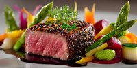 Seared beef steak with herb crust served alongside fresh asparagus and colorful vegetables on elegant plate for gourmet dining and culinary presentations.