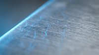 Macro close-up of metallic surface with blue light reflection and fine texture details, suitable for technology, industrial, and abstract design projects.