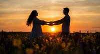 Romantic couple holding hands in sunflower field at golden sunset, silhouetted against warm sky for love and relationship concepts.