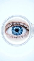 Close-up of bright blue eye with long eyelashes viewed through magnifying glass on white background for vision and optical concepts.