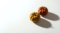 Two decorative autumn pumpkins in orange and yellow colors casting shadows on white background for seasonal fall harvest decoration and holiday design.