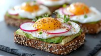 Healthy breakfast sandwich with sunny side up egg, avocado, radish slices and microgreens on seeded bread, served on black slate board. Fresh morning meal.