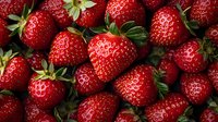 Fresh ripe strawberries with green leaves in natural lighting, close up view showing texture and vibrant red color, arranged in organic pattern for food photography.
