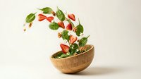 Fresh caprese salad ingredients flying from wooden bowl with mozzarella cheese, cherry tomatoes, basil leaves and nuts creating dynamic food motion.