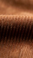 Close-up macro shot of brown knitted wool fabric texture showing detailed ribbed pattern and soft fibers for cozy autumn winter fashion backgrounds.