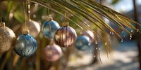 Festive Christmas ornaments hanging from palm fronds with water droplets, creating tropical holiday atmosphere for seasonal decorating.