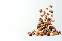 Mixed nuts and seeds falling into pile on white background, including cashews, almonds, walnuts, and hazelnuts. Healthy protein-rich snack concept.