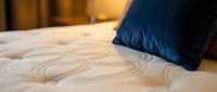 Comfortable mattress with quilted surface pattern and navy blue pillow on top, suitable for bedroom interior design and bedding product marketing.