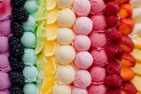 Colorful rows of ice cream scoops arranged in rainbow pattern with fresh fruits and berries including blackberries, kiwi, mango, vanilla, strawberry and raspberry.