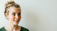 Young woman with blonde hair styled in braided updo, wearing green top, smiling at camera against white background. Suitable for beauty, lifestyle, and portrait projects.