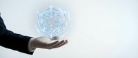 Businessman hand presenting glowing digital shield icon representing cybersecurity, data protection and business security solutions for corporate safety.