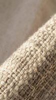 Close-up of natural woven textile with diagonal weave pattern, showing beige linen or cotton fabric texture for interior design and home decor projects.